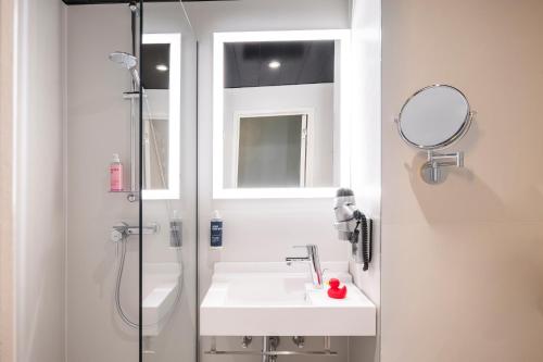 a bathroom with a sink and a shower with a mirror at Thon Hotel Brussels Airport in Diegem