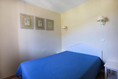 - une chambre avec un lit bleu et deux photos sur le mur dans l'établissement Résidence le Hameau des Issambres - maeva Home - 2 Pièces 6 Personnes Sélection MAE-0735, aux Issambres