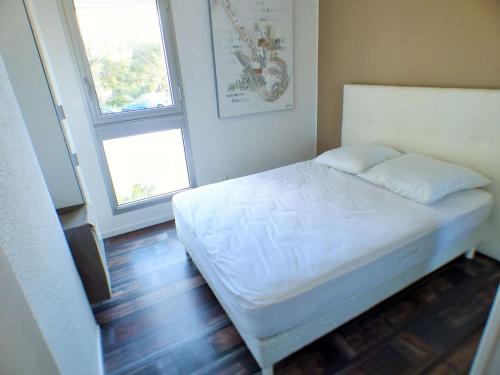 - une petite chambre avec un lit blanc et 2 fenêtres dans l'établissement Appartement refait à neuf, résidence avec piscine à Saint Mandrier village, à Saint-Mandrier-sur-Mer