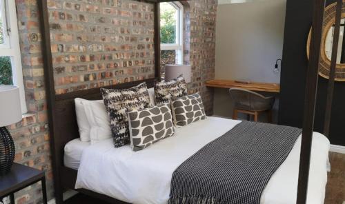 um quarto com uma cama e uma parede de tijolos em CLEMENT ONE, a villa for family & friends em Cidade do Cabo