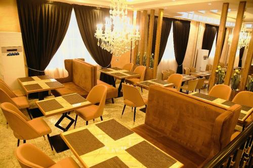 un ristorante con tavoli, sedie e lampadario a braccio di WosAm Hotels a Ago Iwoye
