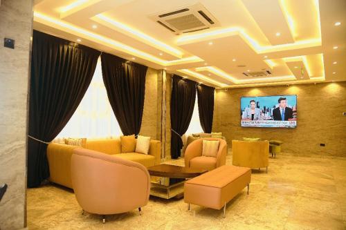 a living room with yellow furniture and a flat screen tv at WosAm Hotels in Ago Iwoye