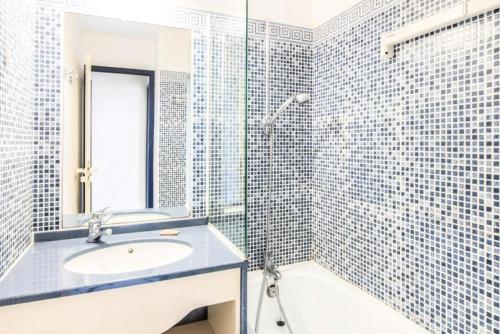 une salle de bain avec un lavabo et une douche avec du carrelage bleu dans l'établissement Résidence Port Bourgenay - maeva Home - 2 Pièces 5 Personnes Confort MAE-1078, à Talmont-Saint-Hilaire