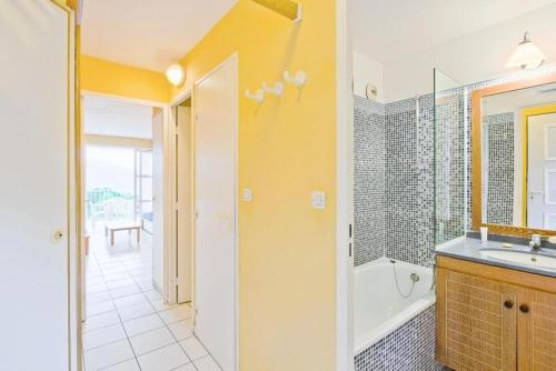 une salle de bain avec une baignoire, un lavabo et un miroir dans l'établissement Résidence le Hameau de Cap Esterel - maeva Home - Appartement 2 Pièces 5 Personnes - Sélection MAE-1109, à Saint-Raphaël