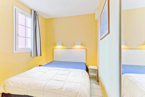 - une petite chambre avec 2 lits et un miroir dans l'établissement Résidence le Hameau de Cap Esterel - maeva Home - Appartement 2 Pièces 5 Personnes - Sélection MAE-1109, à Saint-Raphaël