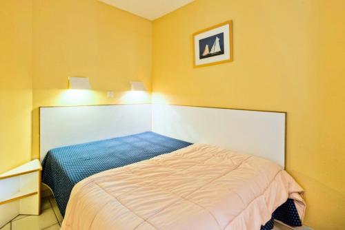um quarto com uma cama num quarto com paredes amarelas em Résidence le Hameau de Cap Esterel - maeva Home - Appartement 2 Pièces 5 Pe 11 em Saint-Raphaël