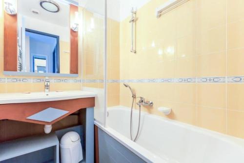 une salle de bain avec un lavabo, une baignoire et un miroir dans l'établissement Résidence Port Bourgenay - maeva Home - 2 Pièces 5 Personnes Sélection MAE-1031, à Talmont-Saint-Hilaire