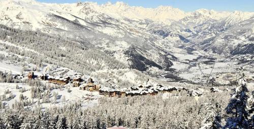 a snow covered mountain with a town in the foreground at Résidence Valbel - Studio pour 6 Personnes 904 in Risoul