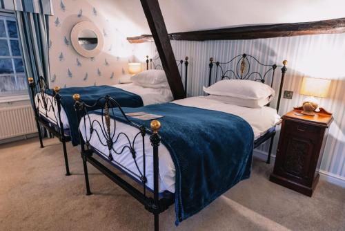 a bedroom with two beds with blue and white sheets at The Bull and Townhouse, Beaumaris- The Inn Collection Group in Beaumaris