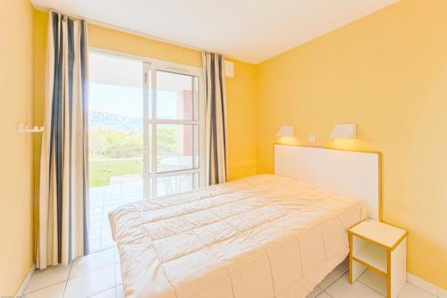 une chambre avec un lit et une grande fenêtre dans l'établissement Résidence le Hameau de Cap Esterel - maeva Home - Appartement 2 Pièces 5 Personnes - Confort MAE-1106, à Saint-Raphaël
