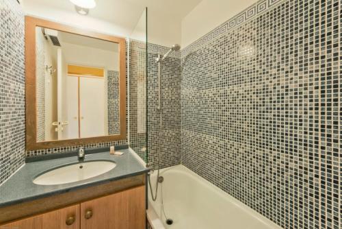 une salle de bain avec un lavabo, une baignoire et un miroir dans l'établissement Résidence le Hameau de Cap Esterel - maeva Home - Appartement 2 Pièces 5 Personnes - Confort MAE-1106, à Saint-Raphaël