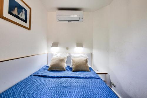 - une petite chambre avec un lit bleu et 2 oreillers dans l'établissement Résidence le Hameau de Cap Esterel - maeva Home - Appartement 2 pièces 4 personnes - Prestige MAE-1164, à Saint-Raphaël