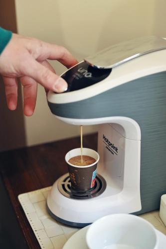 a person pouring a cup of coffee into a espresso machine at Cataneasy Rooms in Catania