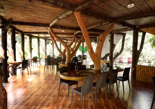 a dining room with a table and chairs and trees at Sahyadri Pride in Wai