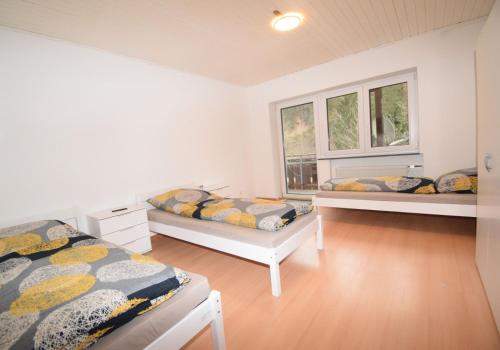1 dormitorio con 2 camas y 2 ventanas en Ferienunterkünfte maucher Immobilien, en Buchenberg