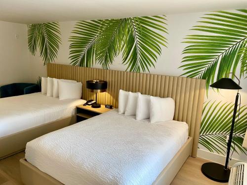 a hotel room with two beds and a palm tree mural at The Harrison Hotel Downtown Hollywood in Hollywood