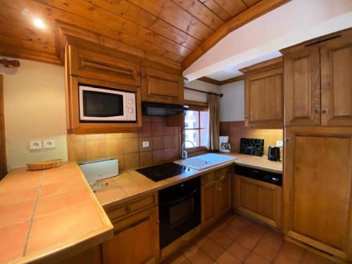 a kitchen with wooden cabinets and a microwave at Résidence Alpina Lodge - 3 Pièces pour 6 Personnes 184 in Vénosc