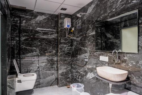 bagno in marmo nero con lavandino e servizi igienici di hotel galaxy a Surat