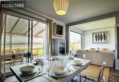 una sala da pranzo con tavolo, sedie e ampia finestra di Sur la plage le bonheur a Plestin-les-Grèves