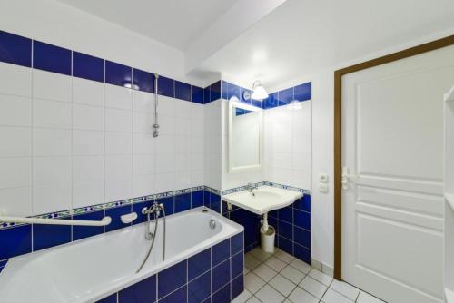 een blauwe en witte badkamer met een bad en een wastafel bij Port du Crouesty Cap'Océan - maeva Home - 2 Pièces 4 Personnes Confort 15 in Arzon