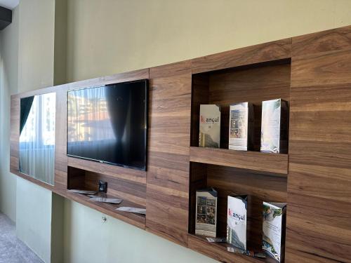 a wooden entertainment center with a tv and books at Kançul Hotel Taştepeler in Urfa