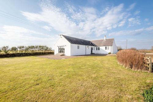 a white house with a large grass yard at Firthview - Crail in Anstruther