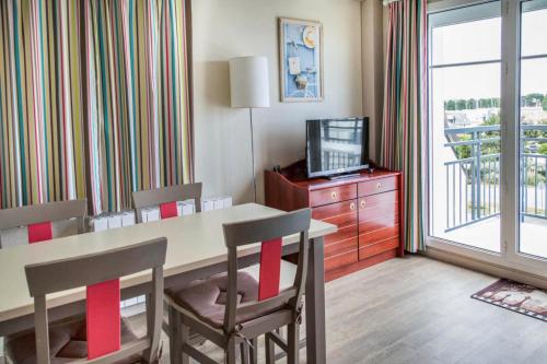 a room with a table and chairs and a television at Résidence Port Guillaume - maeva Home - 3 Pièces 6 Personnes Sélection MAE-1552 in Dives-sur-Mer