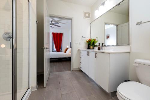 La salle de bains est pourvue de toilettes, d'un lavabo et d'un miroir. dans l'établissement Modern Nulu 2BR CozySuites Unit 03, à Louisville