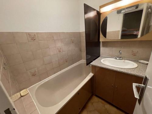 une salle de bain avec une baignoire, un lavabo et un miroir dans l'établissement 150 m de la plage, vue mer et pinède..., à Saint-Elme