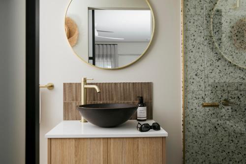 a bathroom with a bowl sink and a mirror at Motel Caloundra in Caloundra