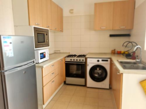 a kitchen with a refrigerator and a microwave and a dishwasher at Remarkable 3-Bed Apartment in Kilamba - Luanda in Luanda
