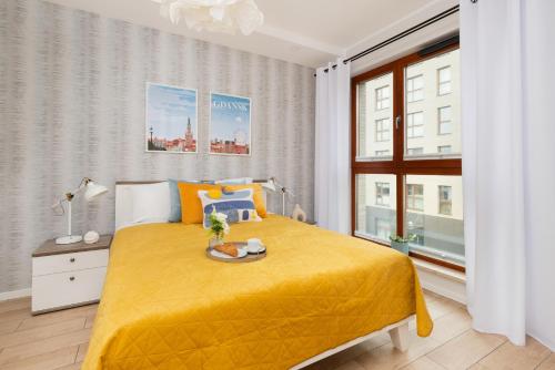 a bedroom with a yellow bed and a window at Zajezdnia Wrzeszcz Modern Apartment with Balcony & Parking Gdańsk by Renters in Gdańsk