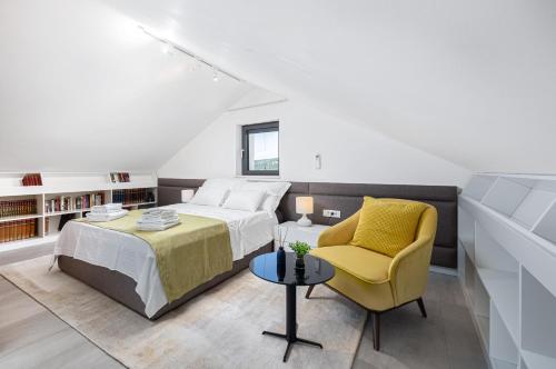 1 dormitorio con 1 cama y 1 silla amarilla en Villa True Oasis with Heated Pool, en Rogoznica