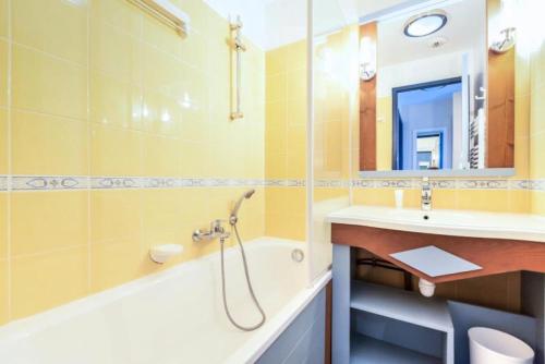 une salle de bain avec un lavabo, une baignoire et un miroir dans l'établissement Résidence Port Bourgenay - maeva Home - Appartement 2 Pièces 5 Personnes - Sélection MAE-2073, à Talmont-Saint-Hilaire