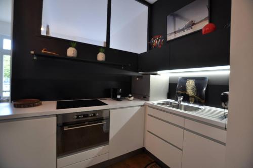 une cuisine avec des armoires blanches, un évier et une cuisinière dans l'établissement HermitageB02, à Le Touquet-Paris-Plage