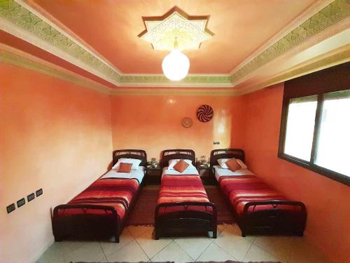 a room with four beds in it with a chandelier at Olympe Surf & Yoga in Tamraght Ouzdar