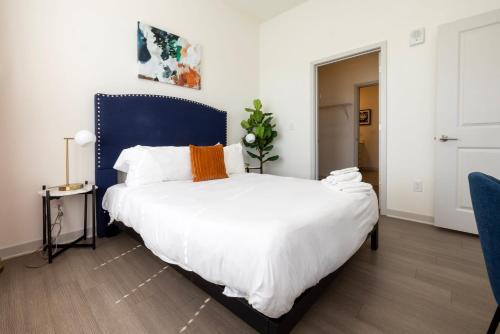 a bedroom with a large bed with a blue headboard at Modern Nulu 2BR CozySuites 04 in Louisville