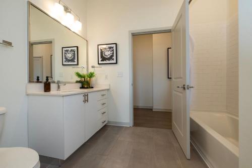 a bathroom with white cabinets and a tub and a sink at Modern Nulu 2BR CozySuites 04 in Louisville