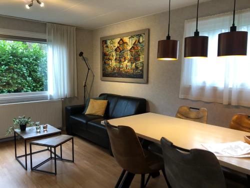 a living room with a table and a couch at Vrijstaand Chalet in Bospark in Hattemerbroek