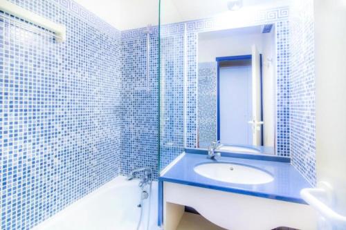 La salle de bains est pourvue de carrelage bleu, d'un lavabo et d'un miroir. dans l'établissement Résidence Port Bourgenay - maeva Home - 2 Pièces 5 Personnes Confort MAE-2110, à Talmont-Saint-Hilaire