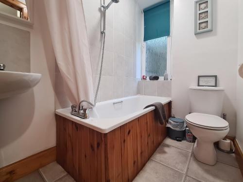 a bathroom with a bath tub and a toilet at Station Cottage in Trinafour