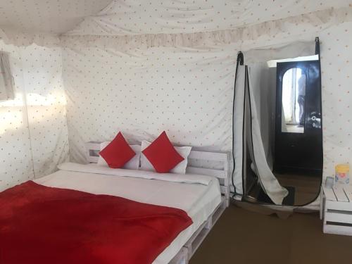 - une chambre avec un lit doté d'oreillers rouges et une fenêtre dans l'établissement Pine Trails Jungle Camp, à Kasauli