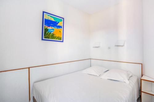 - une chambre avec un lit blanc et une photo sur le mur dans l'établissement Résidence le Village de Cap Esterel - maeva Home - Appartement 2 Pièces 5 Personnes - Confort MAE-2137, à Saint-Raphaël