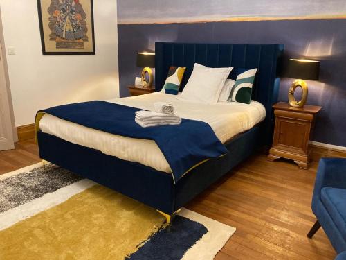 a bedroom with a large bed with a blue headboard at La Villa des Roses Gîte Chambres d'hôtes Piscine chauffée in Luçon