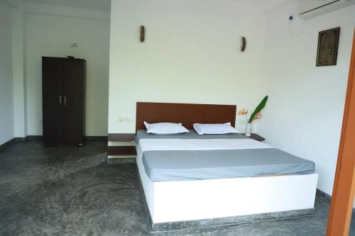a bedroom with a white bed and a black cabinet at Karu's place in Hikkaduwa
