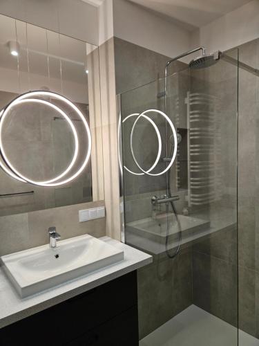 een badkamer met een wastafel en een glazen douche bij Apartamenty Orawska 14 in Krakau