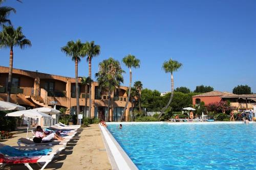 - une piscine avec des chaises longues et des palmiers dans l'établissement Résidence Les Rives de Cannes Mandelieu - maeva Home - 2 Pièces 5 Personnes Prestige MAE-2168, à Mandelieu-la-Napoule