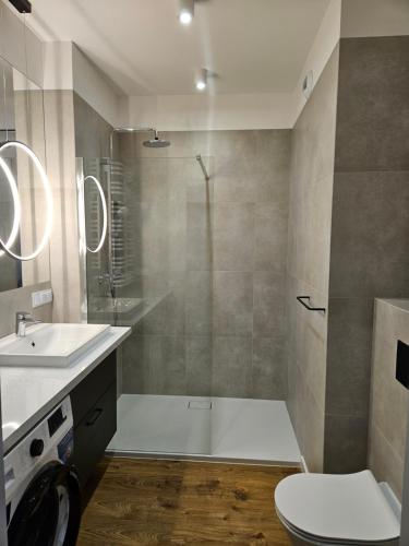 een badkamer met een douche, een toilet en een wastafel bij Apartamenty Orawska 14 in Krakau