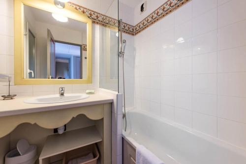 une salle de bain avec un lavabo, une baignoire et un miroir dans l'établissement Résidence Les Rives de Cannes Mandelieu - maeva Home - 2 Pièces 5 Personnes Prestige MAE-2168, à Mandelieu-la-Napoule