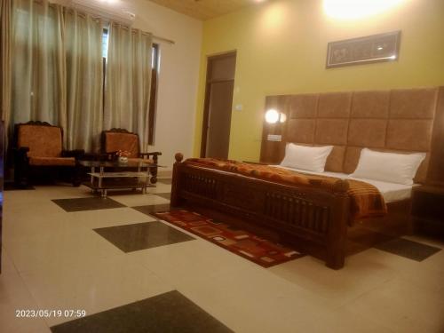 um quarto com uma cama e uma cadeira num quarto em KAMAKSHI GUEST HOUSE em Baijnāth